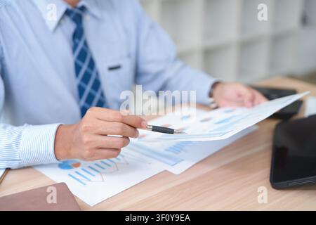 Business professional analyzing financial reports and charts at Stock Photo