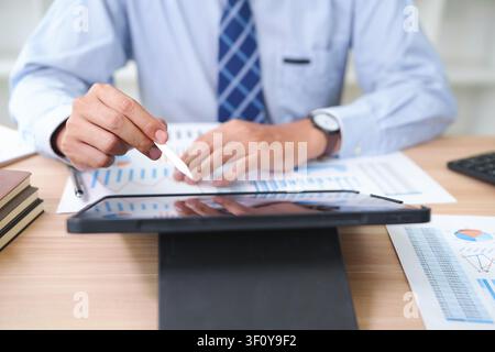 Businessman Analyzing Financial Data on Digital Tablet and Paper Stock Photo
