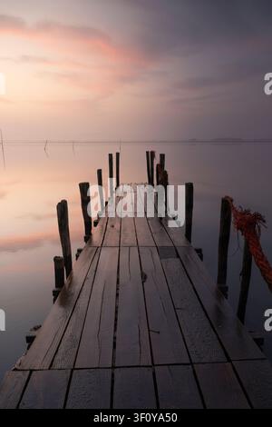 Old wooden pier on a calm lake at sunrise Stock Photo