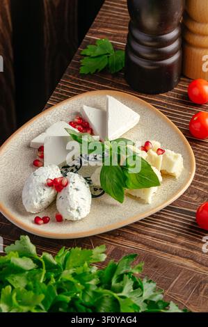 Gourmet cheese plate with pomegranate and fresh basil Stock Photo