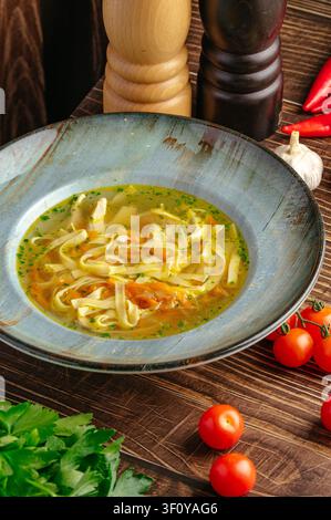 Chicken noodle soup in a blue bowl on a wood table Stock Photo