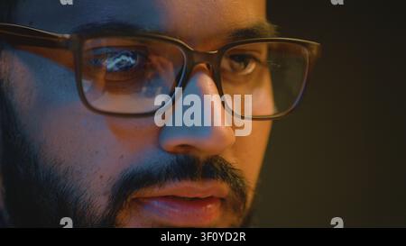 Concentrated Indian business man male wearing glasses with reflected graph reflection computer data analytics working at night office Arabian Stock Photo