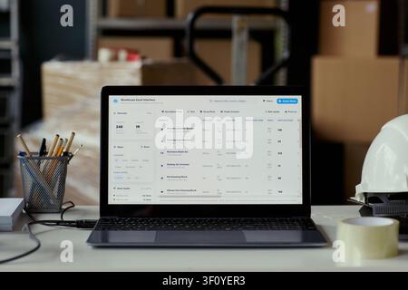 Close up of laptop displaying warehouse inventory dashboard on desk in storage facility, managing stock data and logistics workflow. Ideal for supply chain software marketing and operations content Stock Photo