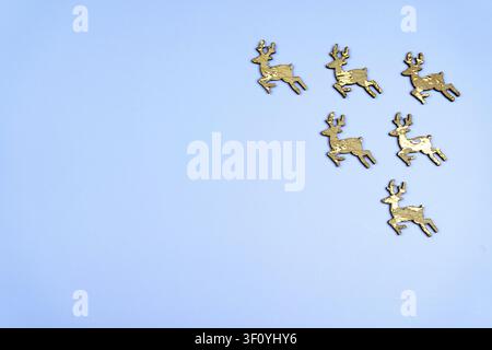 Golden reindeer Christmas decorations on a soft blue background with copy space. Minimal winter holiday flat lay. Stock Photo