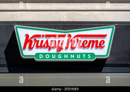 Sign and logo at the entrance of a Krispy Kreme store. Krispy Kreme, Inc.  is an American doughnut company and coffeehouse chain Stock Photo