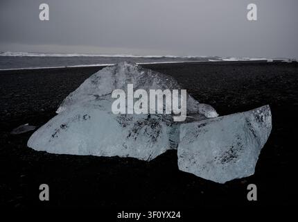 Glacial ice chunks rests on Diamond Beach’s black volcanic pebble shore Stock Photo