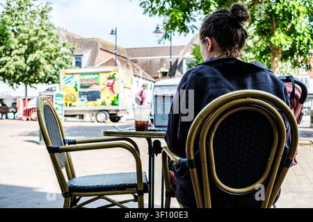 London UK, July 10 2026, A Young Female Freelancer Working On Her Laptop Computer While Enjoying An Iced Coffee At An Outdoor Cafe On A Summer Day Stock Photo
