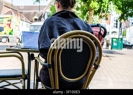 London UK, July 10 2026, A Young Female Freelancer Working On Her Laptop Computer While Enjoying An Iced Coffee At An Outdoor Cafe On A Summer Day Stock Photo