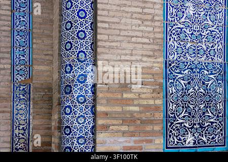 Ornate blue ceramic tilework and brick wall detail at Islam Khoja Madrasah in Khiva. Intricate geometric and floral patterns in traditional Uzbek arch Stock Photo