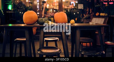 Pumpkins and decorative gourds on restaurant tables create a cozy autumn evening atmosphere with seasonal fall decor. Stock Photo