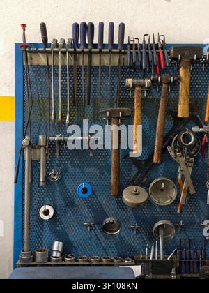 Various mechanic hand tools organized on a blue perforated pegboard Stock Photo