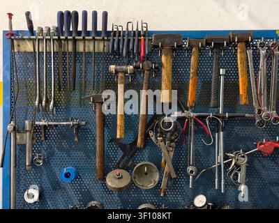 Hand tools and diagnostic equipment hanging on a blue pegboard wall Stock Photo