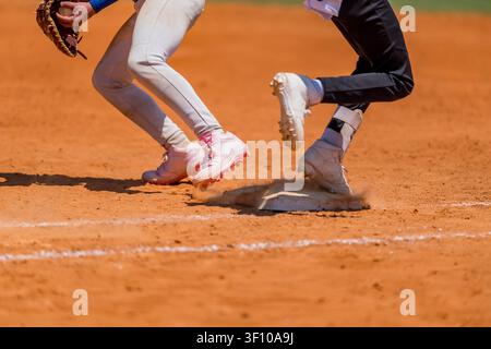 A baseball player sprints toward first base after making solid contact, racing down the line as the defense reacts during an exciting youth baseball g Stock Photo