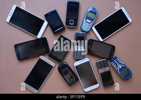 A composition featuring various cell phones from different generations alongside a current smartphone. Stock Photo