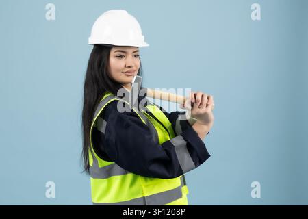 Female engineer in a hardhat and safety vest holding a tool hammer Stock Photo