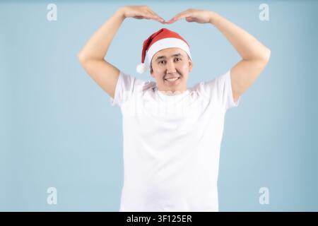 Young man making heart shape above head celebrating christmas Stock Photo