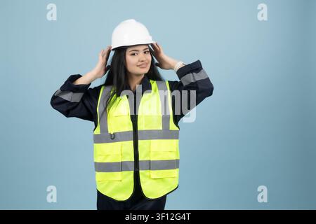 Stressed female engineer in a hardhat holding her head in trouble Stock Photo