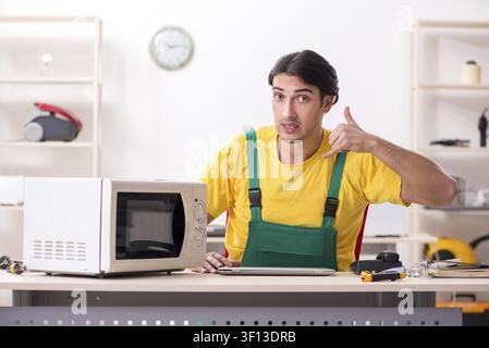 Young repairman repairing microwave in service centre Stock Photo
