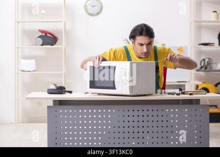 Young repairman repairing microwave in service centre Stock Photo