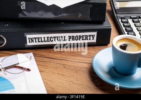 Intellectual Property label on folder and up of coffee on wooden table, closeup Stock Photo