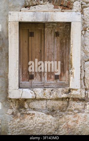 A shuttered window in an old abandoned brick house Stock Photo