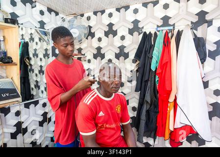 Teenage barber trimming a customer's hair, Ghana Stock Photo