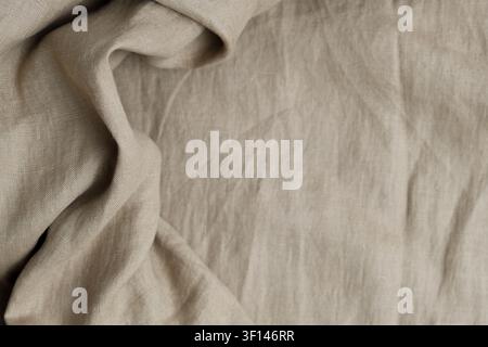 Wrinkled beige natural linen fabric texture background with draperies. Top view Stock Photo