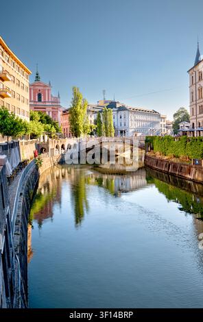 The Ljubljanica River, Triple Bridge and Franciscan Church of the Annunciation reflected in calm water in Ljubljana, Slovenia. Stock Photo