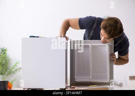Young handsome contractor repairing fridge Stock Photo