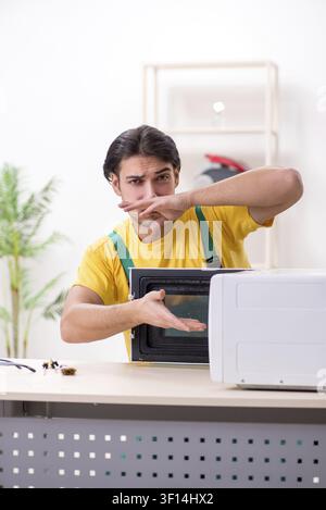 Young repairman repairing microwave in service centre Stock Photo