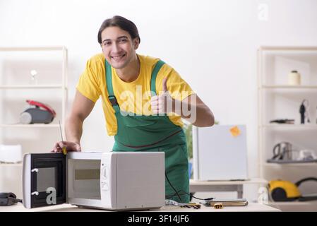 Young repairman repairing microwave in service centre Stock Photo