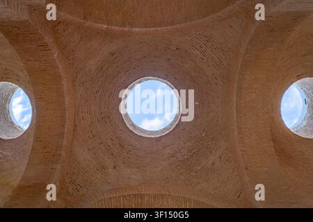 A close view looking up shows two circular oculus openings in the sandstone vaulted dome of the Fondouk Semmarine, each framing a patch of blue sky an Stock Photo