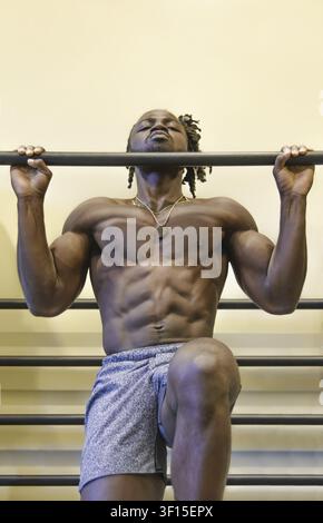 Handsome, young, muscular African American man, a bodybuilder, doing pull-ups in the gym Stock Photo