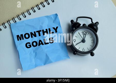 Concept of monthly goals write on sticky notes isolated on Wooden Table. Stock Photo