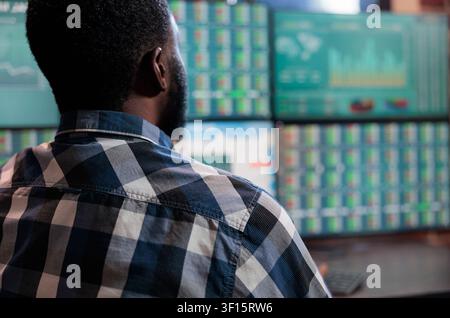 Investment broker analyzing real time market statistics in a brick wall trading office combining market monitoring, financial technology and professional risk analysis. Stock Photo