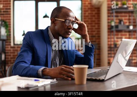 Businessman uses a laptop to analyze marketing strategy and brainstorm project solutions during focused office work at a desk, showing professional workflow and commercial workplace communication. Stock Photo