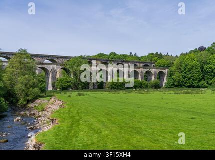 Two people walk in a field below the impressive Chirk Aqueduct and Viaduct, a UNESCO World Heritage site in rural Shropshire. Stock Photo