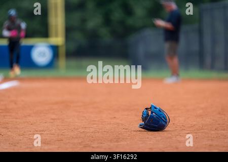 A lone catchers mask rests quietly on the baseball diamond between innings at a local youth tournament, symbolizing teamwork, anticipation, and the ti Stock Photo