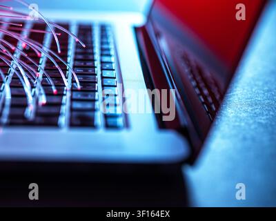 Fibre optics carrying data to a laptop. Stock Photo