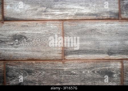 High-resolution close-up of dark grey ceramic floor tiles imitating aged wood plank design. High quality porcelain tiles with natural grain pattern, s Stock Photo