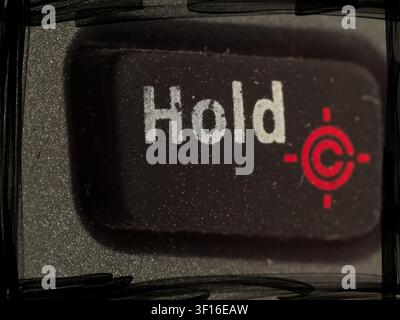 Macro closeup of a rectangular black Hold button with printed white text and a red target icon on a textured device panel Stock Photo