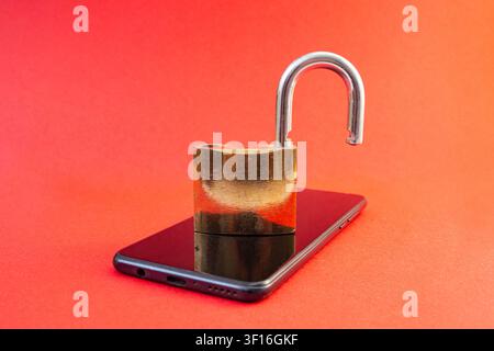 Open golden pad lock on a black smartphone   on orange background , cyberspace  concept Stock Photo