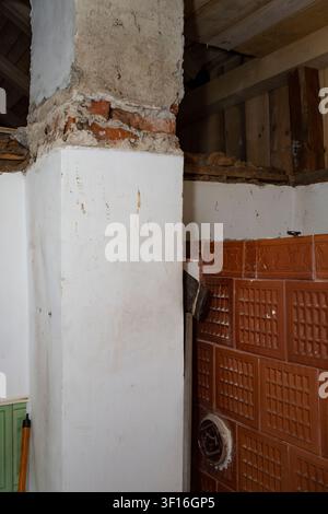 Old Brick Chimney Demolition and Restoration with Vintage Tiled  Stove Stock Photo