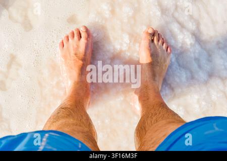 Close-up POV male tourist walking on the unique salt formations and turquoise mineral-rich waters of the Dead Sea beach. A concept for wellness, healt Stock Photo