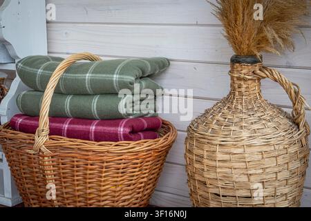 Folded wool blankets in wicker basket creating cozy rustic home interior storage Stock Photo