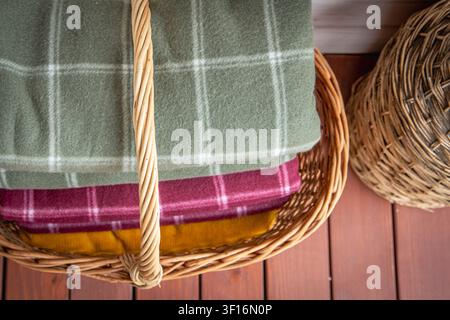 Folded wool blankets in wicker basket creating cozy rustic home interior storage Stock Photo