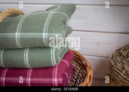 Stack of folded wool blankets in wicker basket creating warm and cozy rustic home interior Stock Photo