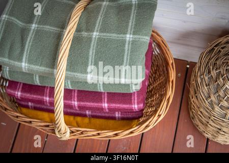 Folded wool blankets in wicker basket creating cozy rustic home interior storage Stock Photo