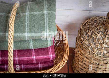 Folded wool blankets in wicker basket creating cozy rustic home interior storage Stock Photo