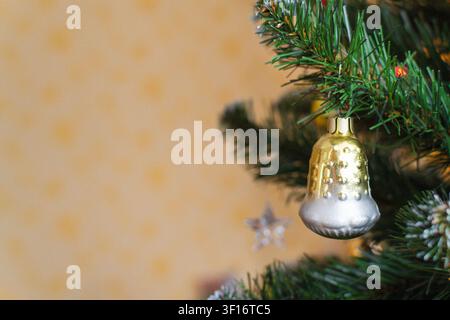 Silver Christmas bell ornament hanging on a fir tree branch with copy space. Holiday tradition and festive celebration concept for seasonal greeting Stock Photo